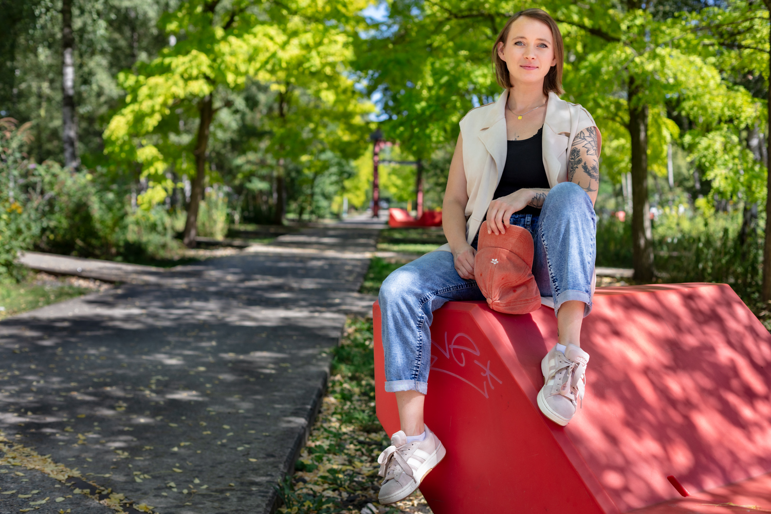 Frau sitzt draußen an der Zeche Zollverein mit Bäumen im Hintergrund