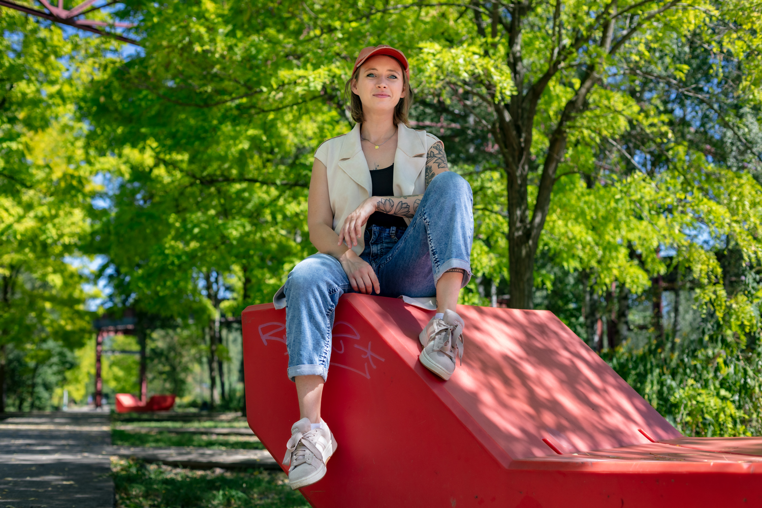 Frau sitzt draußen auf rotem Objekt